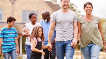 Multiracial and multigenerational family walking together in front of house