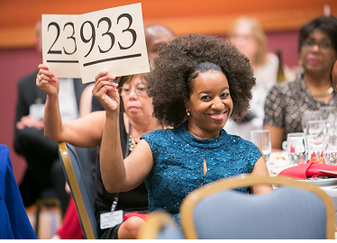 Photo of a woman bidding at an event auction. 