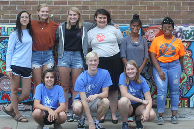 Youth group in front of brick wall mural 
