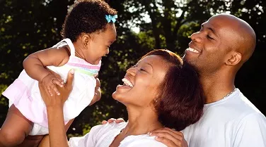 Family smiling holding infant.