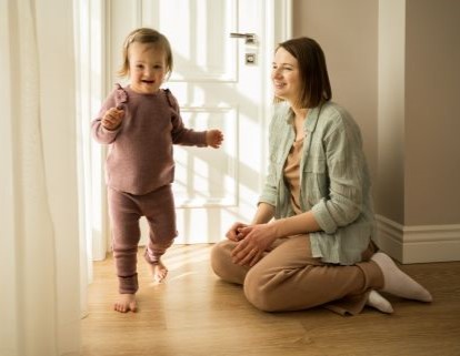 Daughter running in the hall with her mother sitting watching her