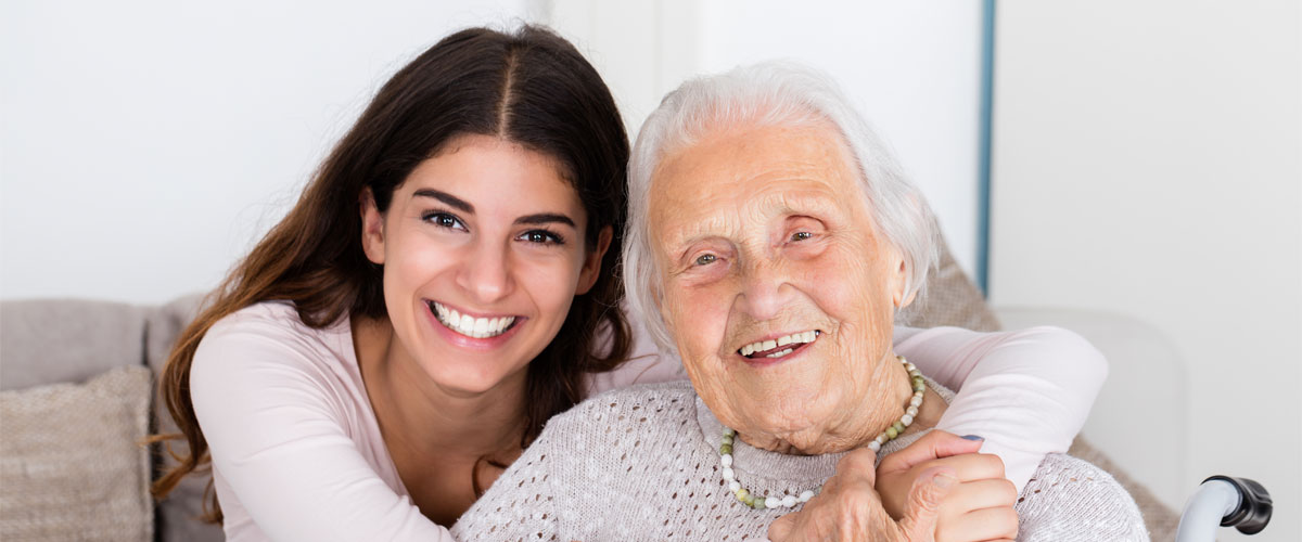 Portrait of grandmother and granddaughter embracing at home.